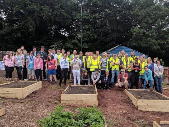 Volunteers stand in an allotment to pose for a photo