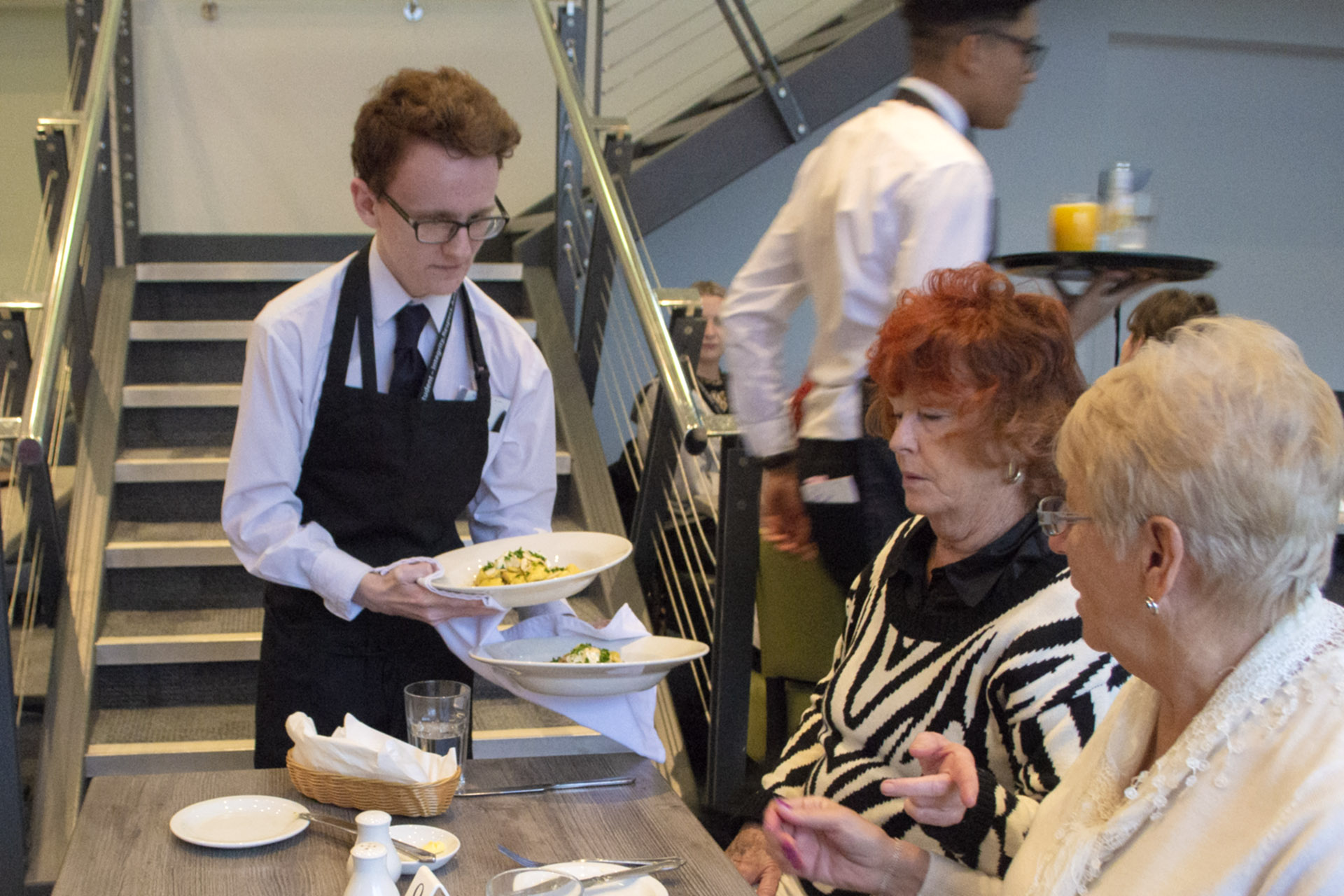 A Hospitality student serving guests at the City Restaurant.