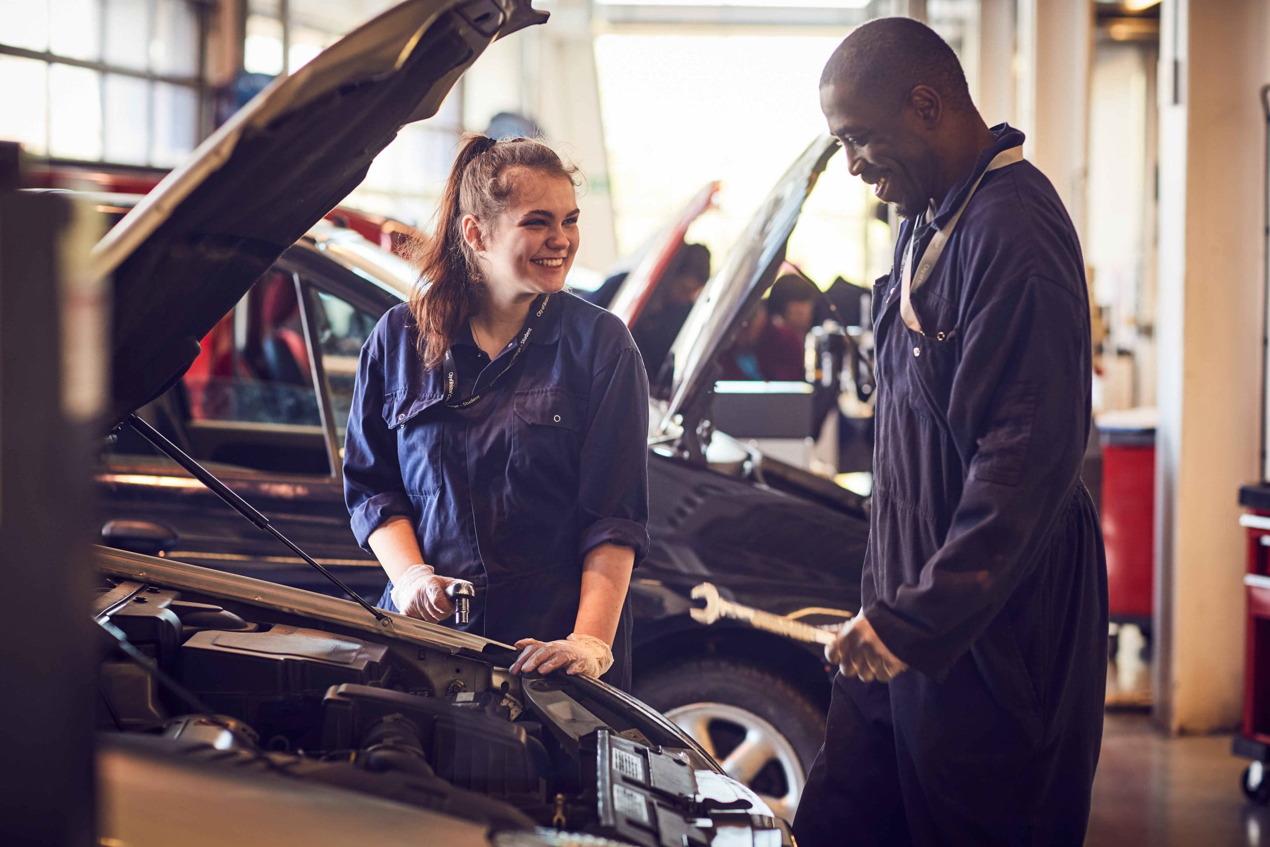 Two people working on car on a mechanics and motor vehicle course