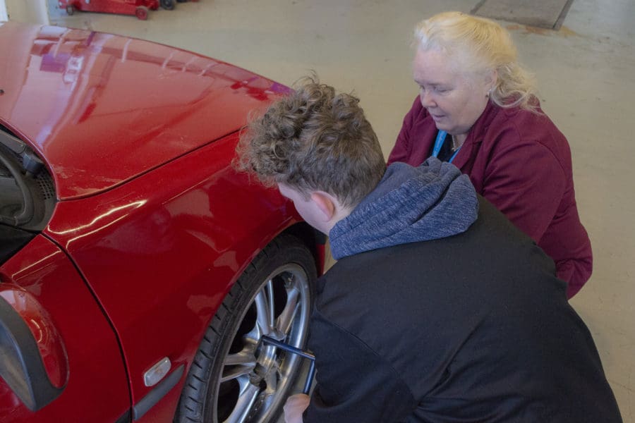 Tutor and student working on car