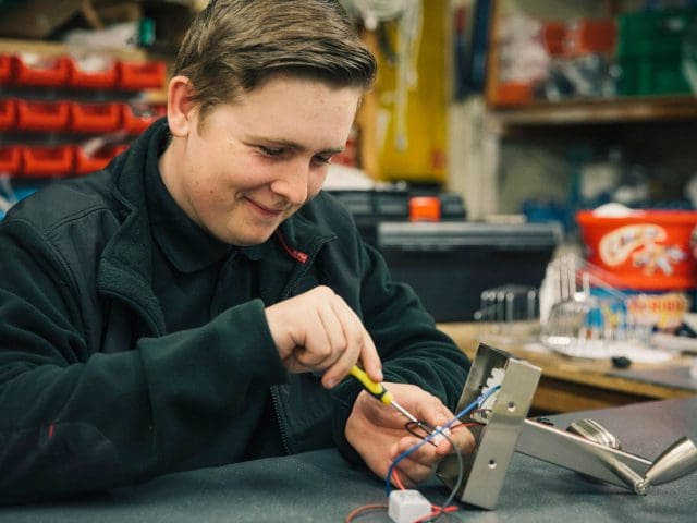 Hilton apprentice, Ross Budd works on some lights at a workbench