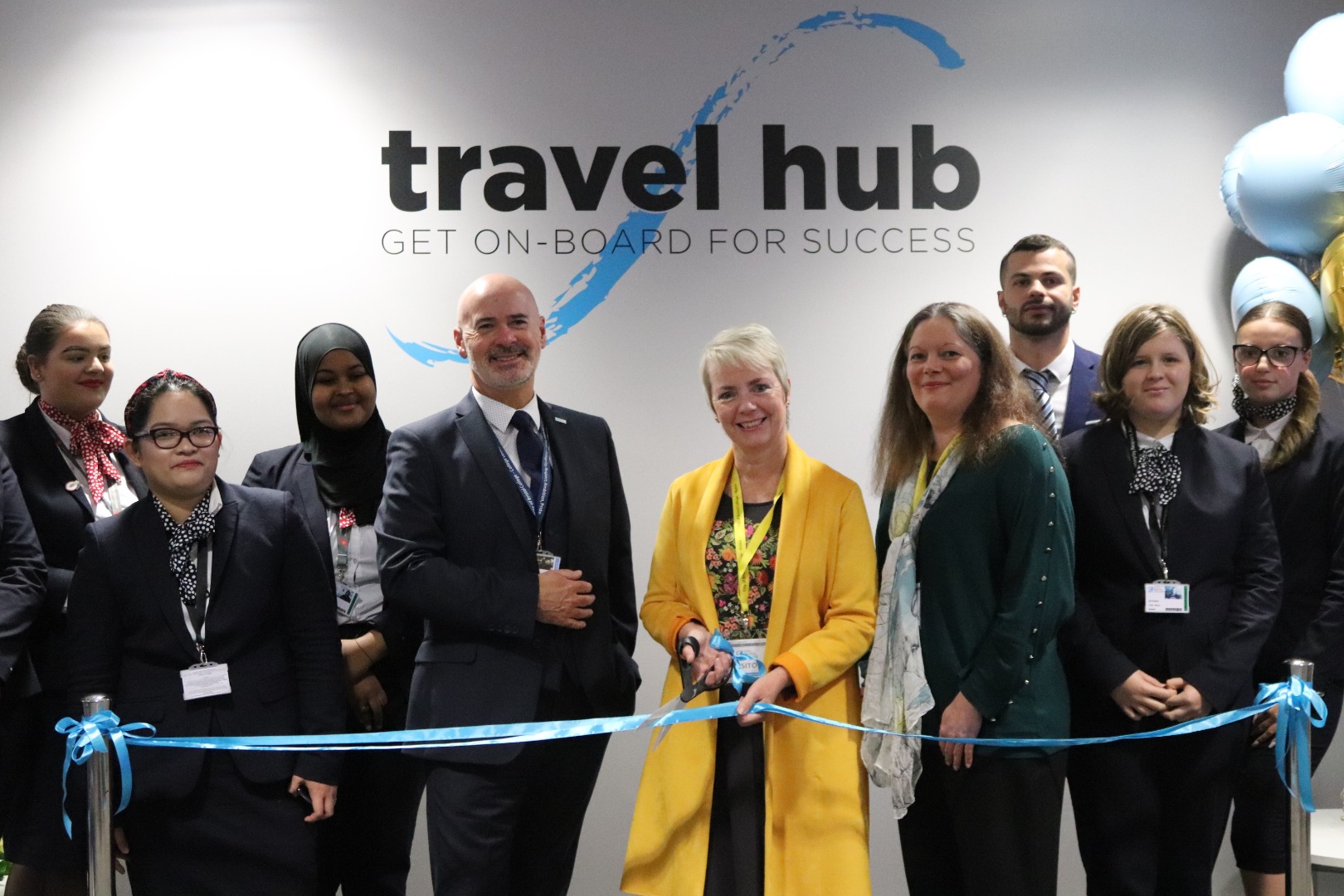 MP Karin Smyth cuts a ribbon for the travel hub. Students and staff are around her