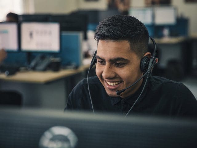 Young man smiles as he answers the phone in a call centre