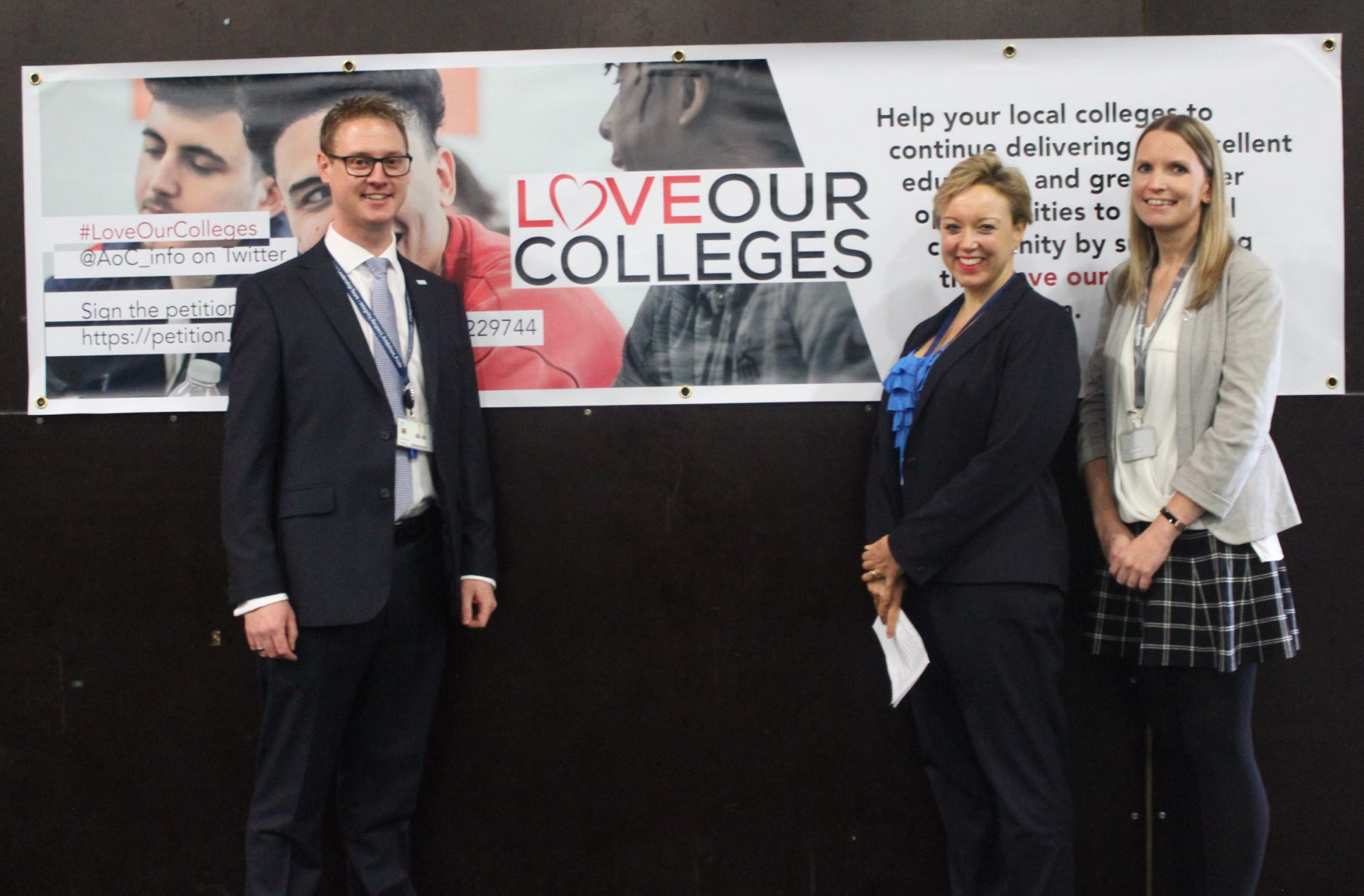 3 members of Bristol staff stand infront of a banner displaying a 'Love Our Colleges' poster with information on the campaign