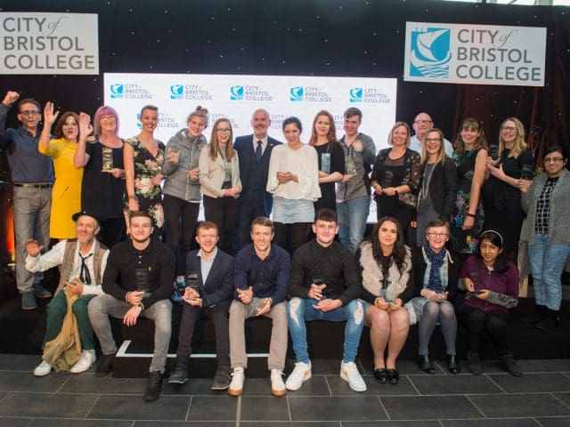 Students of City of Bristol College celebrate on stage as they hold their awards