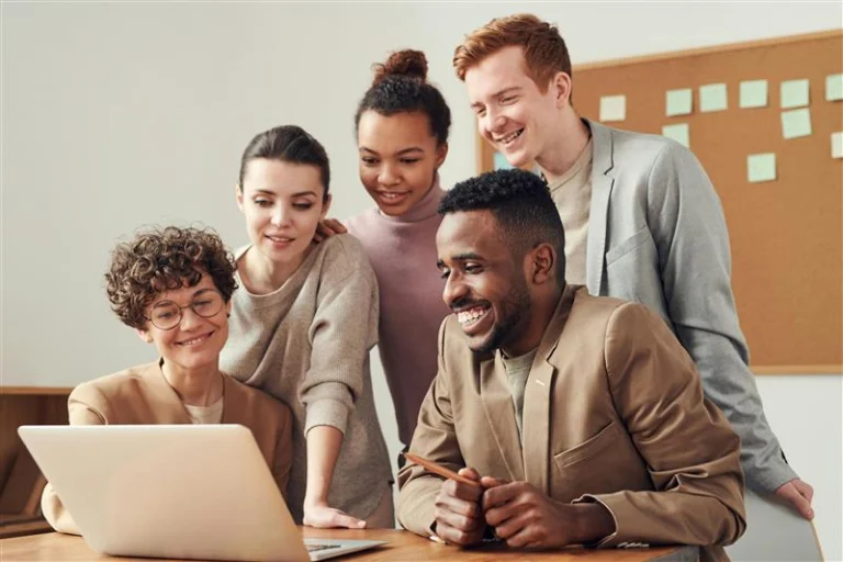 Friends gathered and smiling at a laptop.