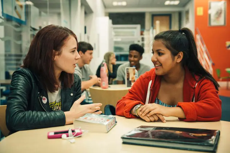 Two female students sat in a table chatting.