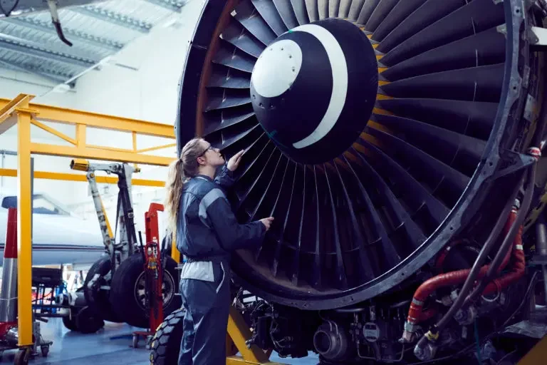 Female Aircraft engineering student working on a big turbine.