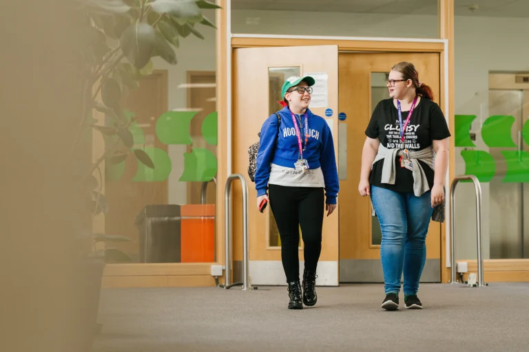 two students walking and chatting with each other smiling