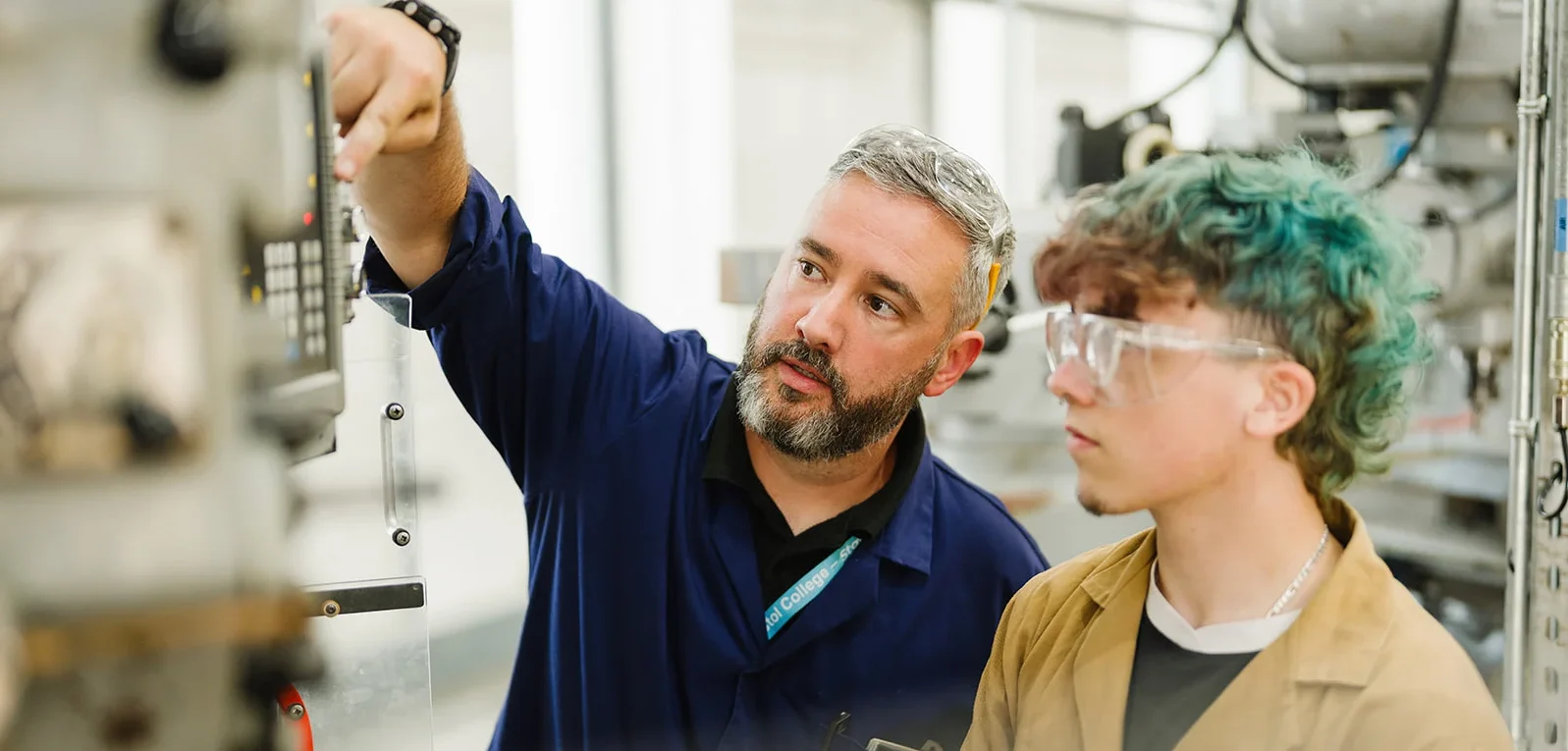 student and lecturer examining an electrical device on the wall