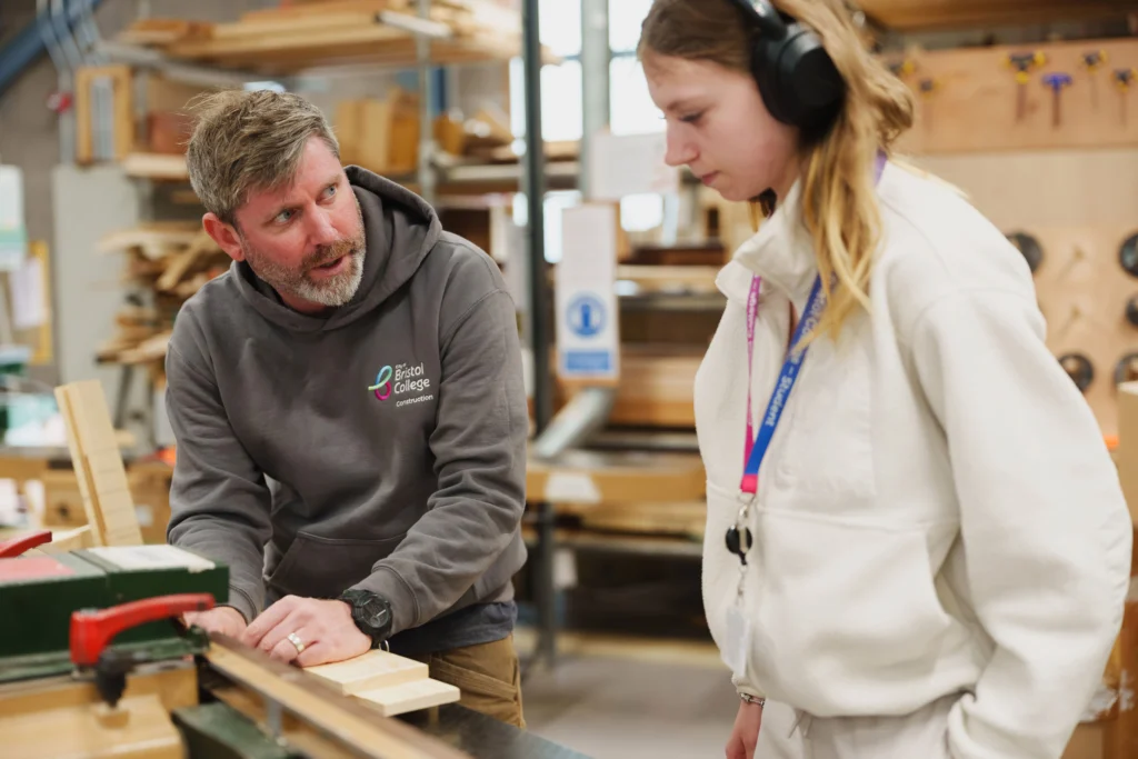 Teacher is talking to a Student with ear protectors on in a workshop enviroment