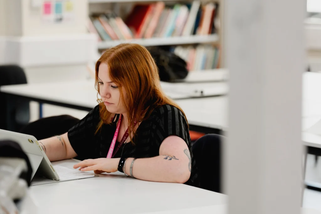 Student looking intently at an iPad while typing on a keyboard.