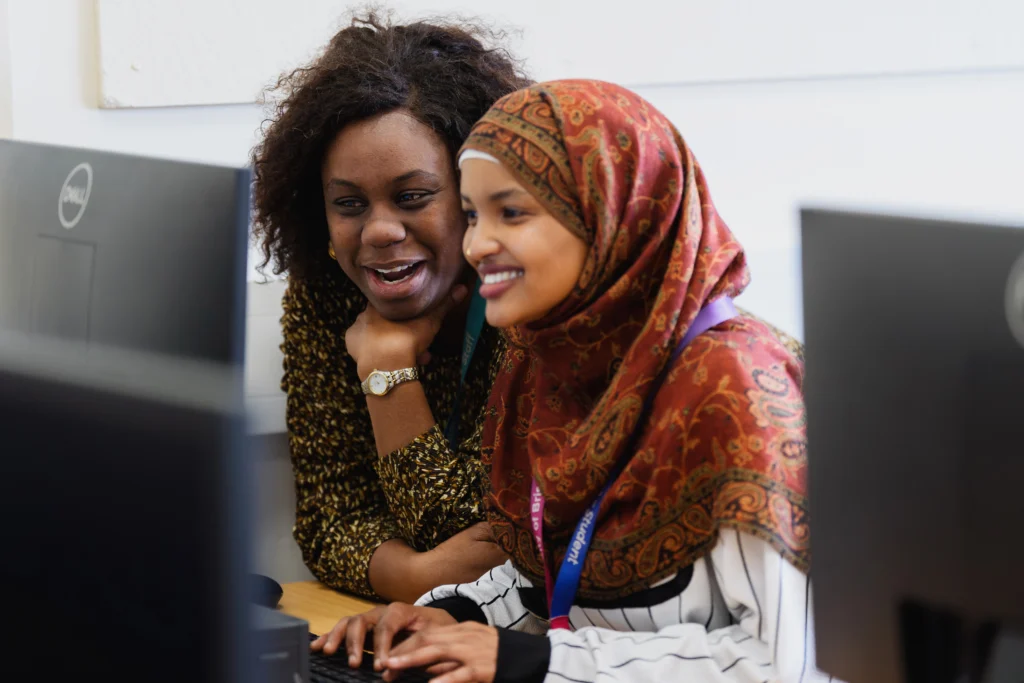Student and teacher looking at a computer and smiling
