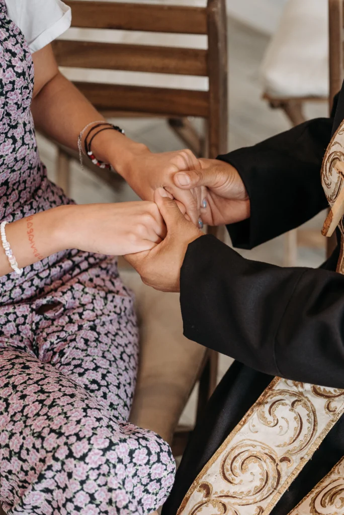 A priest holding hands of a woman in prayer