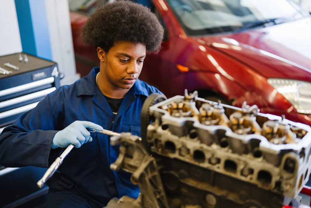 A student in a garage fixing an engine