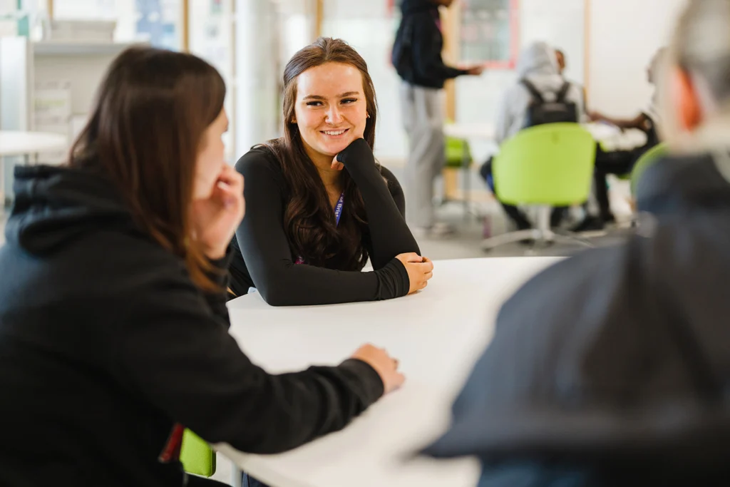 Students sat at a a table smiling