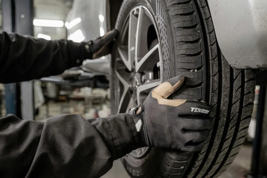 Auto-care technician pulling a wheel out of a car