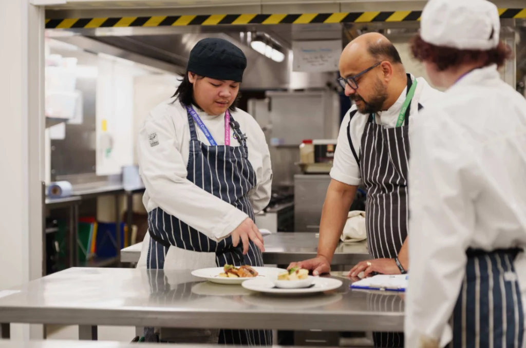 Catering student talking to his teacher about a food plate