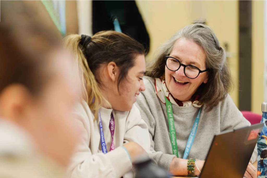 Teacher talking to a student and smiling in a classroom setting